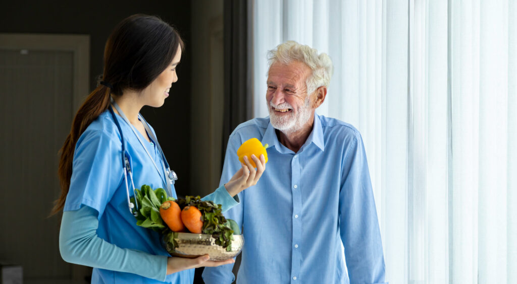 Jeune femme tend un fruit à un vieil homme qui rit