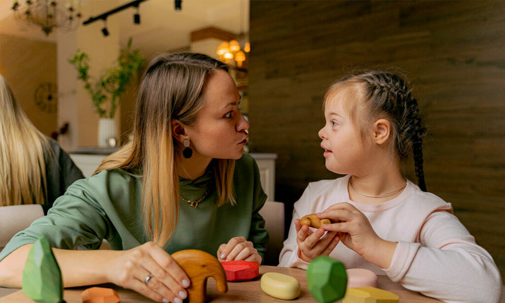Baby-sitter et jeune fille handicapée s'amuse en faisant des grimaces ensemble