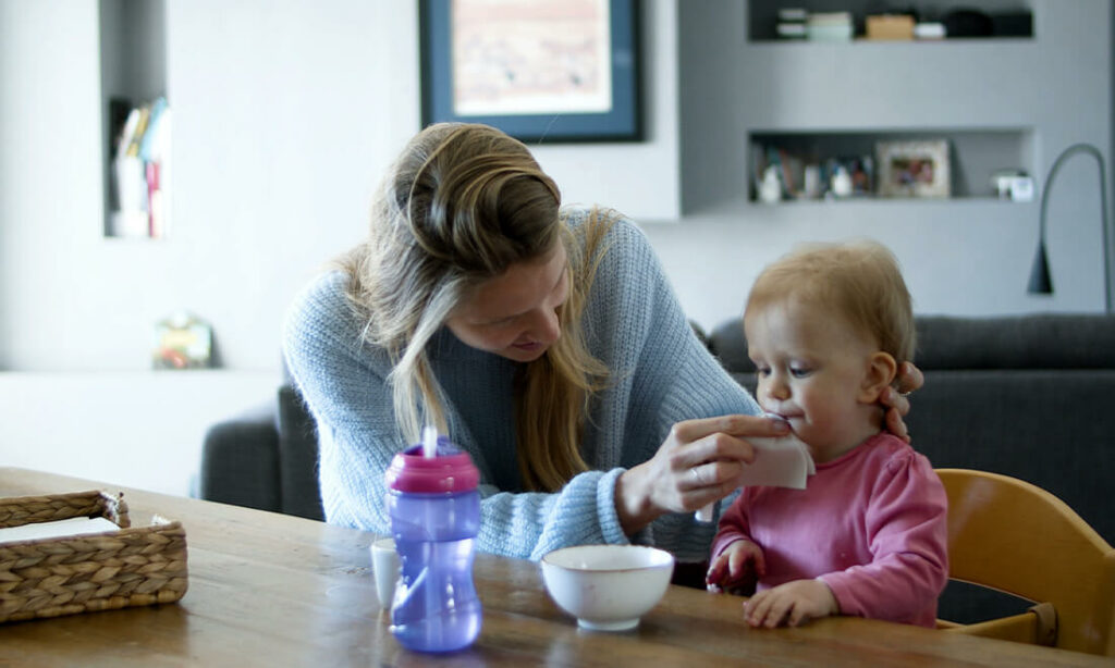 Baby-sitter essuie la bouche d'une enfant après son repas