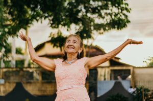 Femme senior lève les mains avec un grand sourire