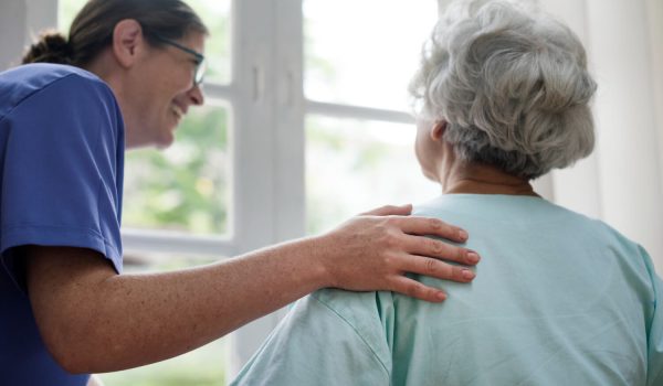 Une femme souriante ayant la main sur l'épaule d'une femme âgée de dos