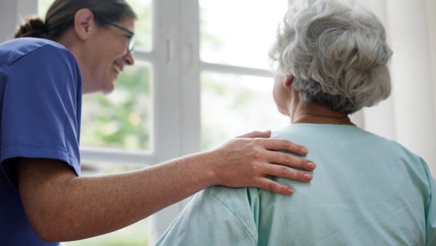 Une femme souriante ayant la main sur l'épaule d'une femme âgée de dos